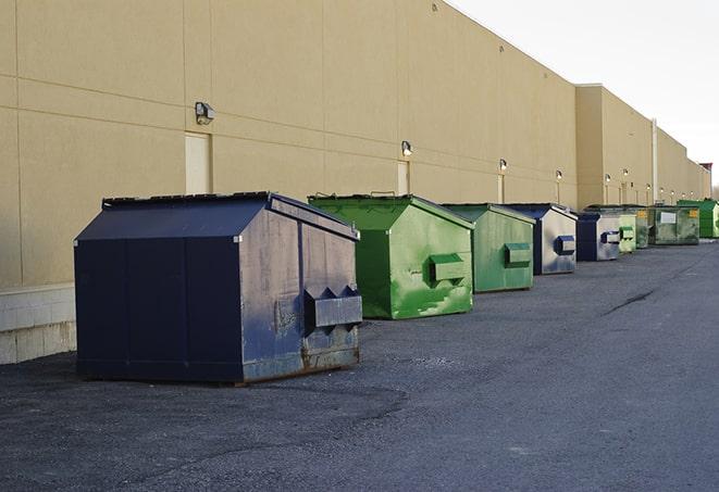 construction workers throw waste into a dumpster behind a building in Mayville